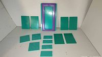 Photo showing lot with one purple frame and 13 green plates arranged on a white surface, illustrating the entire set.