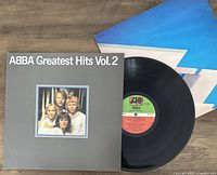 Vinyl LP record of ABBA Greatest Hits Vol. 2 with grey cover featuring band photo and original paper inner sleeve with blue design.