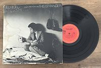 Front cover of Billy Joel's 'The Stranger' vinyl LP album with record partially removed showing red label.