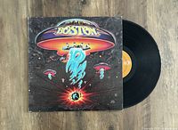 Boston vinyl LP with iconic spaceship album cover laid flat on wooden floor.