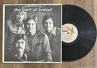 Black vinyl LP record alongside its original album cover featuring a black and white photo of the band Bread.
