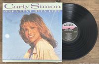 Photo shows Carly Simon Greatest Hits Live vinyl LP record partially out of the album cover, with a clear image of Carly Simon on the cover and the Arista label on the record.