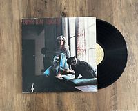 Photo of Carole King Tapestry vinyl LP album with the cover featuring Carole King sitting near a window with a cat, the vinyl record partly visible.