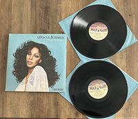 Two vinyl LP records and one album cover for Donna Summer's Once Upon A Time album laid flat on a wooden surface, showing front cover and record labels.
