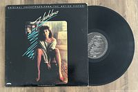 Photo of the Flashdance OST vinyl record partially out of its sleeve, showing both cover art and vinyl disc.