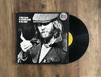Black and white cover photo of Harry Nilsson holding a cigar, album title visible on top left corner, original record partially visible.