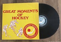 Top view of the yellow vinyl LP cover 'Great Moments of Hockey' and the black vinyl disc partially removed from its sleeve.