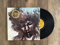 Vinyl LP record and cover with artistic portrait of Jimi Hendrix, yellow label visible on disc.