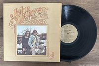 Shows the front of the album cover along with the vinyl record partially out of the sleeve.