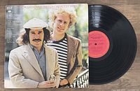 Simon & Garfunkel Greatest Hits Vinyl LP record and album cover placed on wooden floor.