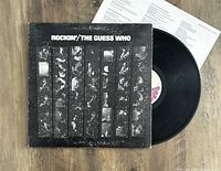 Photo of The Guess Who 'Rockin'' vinyl LP with album cover and insert on a wooden floor.