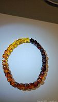Photo showing the full view of the Baltic amber bracelet featuring gradient colors from honey yellow to dark brown beads on stretchy band.