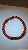 Fire red Carnelian bead stretchy bracelet laid out in a circle, showing color and bead size clearly under white lighting.