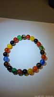 Front view of the multicolored agate bead bracelet laid flat on a white background showing the bead colors and elastic thread.