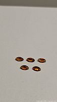 Five marquis cut Madeira citrine gemstones laid out on a white background showing their deep orange-brown color and clarity.