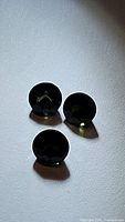Three round deep green natural tourmaline gemstones shown from top view, displaying rich color and cut.