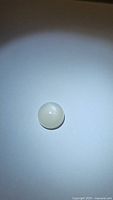 Photo of 6.51ct natural white moonstone, round cabochon, approximately 12mm diameter, showing good flash.