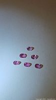 Photo showing six small oval pink sapphires arranged in two rows, highlighting color and clarity.