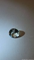 Photo of a light green transparent diamond cut prasiolite green amethyst gemstone placed on a white surface.