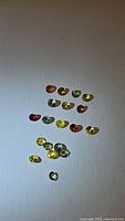 Clear image of all rainbow sapphire stones arranged in a single group on white background showing colors and sizes.