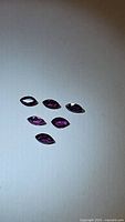 Six marquis cut deep purple sapphires laid out on a white surface, showing clarity and cut.