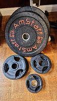 Full view of all the weight plates arranged on the floor showing two large Amstaff 15lb plates and smaller black Northern Lights plates