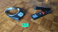 Photo showing both head magnifier and heavy duty stapler on wooden floor, labeled #12.