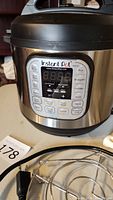 Front view of Instant Pot IP-Duo with digital control panel and multiple cooking options visible.
