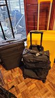 Three luggage pieces grouped: yellow hard shell, grey fabric spinner, black tote