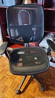 Front view of black mesh office chair showing breathable mesh seat and backrest, armrests, and wheels.