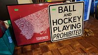 Framed Toronto map print and reflective metal street sign side by side on floor, showing size and condition