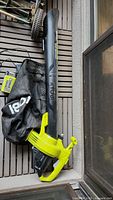 Full view of Ryobi Vacattack leaf mulcher with attached black collection bag and battery pack inserted.