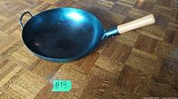 Full view of the wok pan showing wooden handle and interior condition.