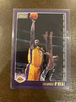 Front of Topps basketball card showing Shaquille O’Neal jumping for a shot in Lakers uniform with purple border and team logo.