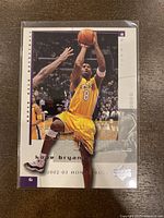 Front view of 2002-03 Upper Deck Honor Roll Kobe Bryant basketball card showing action photo of Kobe mid shot in Lakers yellow jersey number 8.