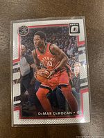 Front view of the 2017-18 Panini Donruss Optic DeMar DeRozan basketball card #136 showing the player in his Toronto Raptors uniform holding a basketball.