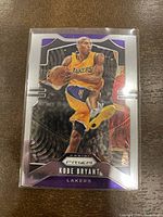 Front of 2019-20 Panini Prizm Kobe Bryant #8 LA Lakers basketball card showing Kobe mid-dribble in Lakers uniform with purple and silver border design.