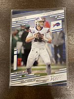 Front view of the 2021 Panini Prestige Josh Allen football card in protective sleeve, showing player in Buffalo Bills uniform with card graphics and logo.