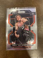 Front of the 2022 WWE Panini Prizm trading card showcasing Bret 'Hit Man' Hart in a wrestling action pose, in protective plastic sleeve.