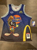 Front view of blue mesh Space Jam basketball jersey featuring Marvin The Martian with Tune Squad text, McDonald's logo, and branding patches, size large.
