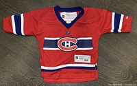 Front view of red Montreal Canadiens infant/toddler hockey jersey by Reebok, showing logo and design details