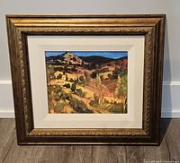 Front angled view of framed Provencal Landscape print depicting a colorful hilly countryside scene in a decorative gold-brown frame with double white matting.
