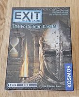 Box of Exit The Game: The Forbidden Castle, sealed and new, showing cover art with medieval knight helmet and torch.
