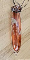 Top down view of the elongated cranberry colored glass bud vase showing the leather straps tied around the neck with no chips or cracks visible.