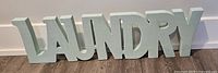 Photo of entire wooden Laundry sign showing pale green paint and block letter design