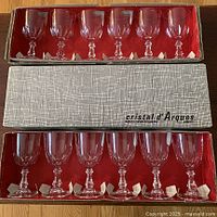 Two open boxes showing 12 lead crystal liqueur glasses, 6 in each box lined with red interior.