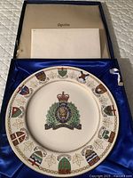 Top-down view of the commemorative collector plate in original box with certificate above it.