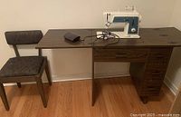 Full view of wooden sewing workstation with chair and Singer sewing machine on top