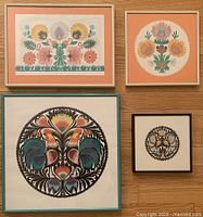 Four framed Polish folk Wycinanki cut outs on wood floor showing details and colors