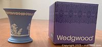Photo showing pale blue Wedgwood Jasperware posy pot next to its original purple Wedgwood branded box.